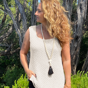 Woman wearing the Elvi loose singlet #101 in ecru with a long tassel necklace