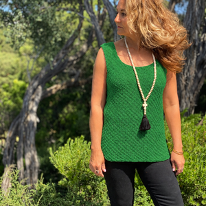 Woman wearing the Elvi loose singlet #101 in emerald green with black trousers