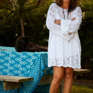 Woman wearing the Lace Tunic #107 in white, knitted in five lace patterns