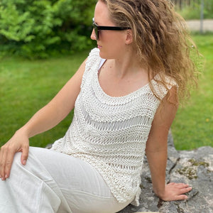 Woman sitting in the Boho drop stitch top #112 in ecru with white trousers