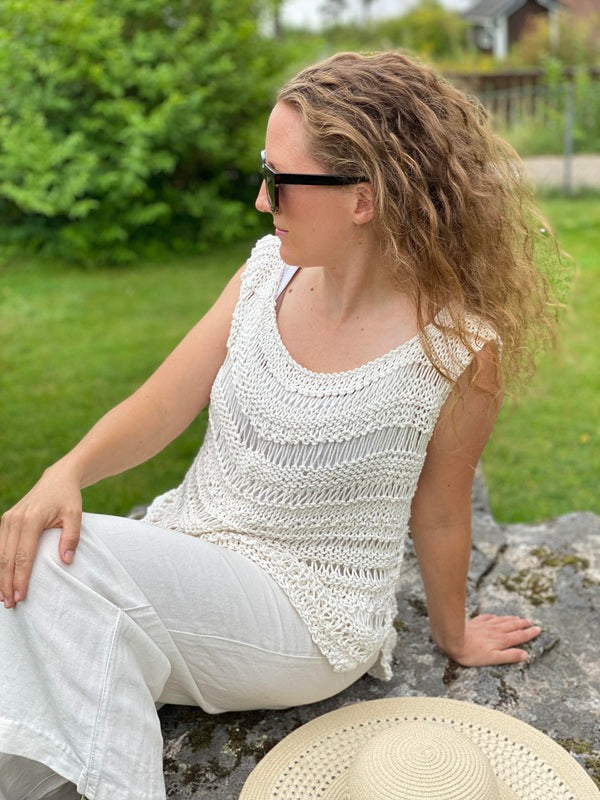 Woman sitting in the Boho drop stitch top #112 in ecru with white trousers