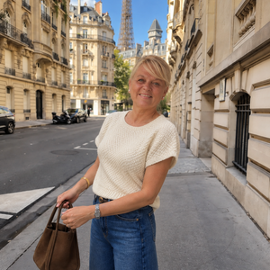 Woman on a city street wearing the Embla knitted t-shirt #132 in ecru with jeans