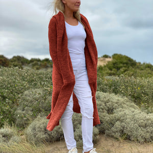 Woman in the dunes wearing the Elna Hooded Cardigan #133 knitted in Scandi Soft XL Terracotta