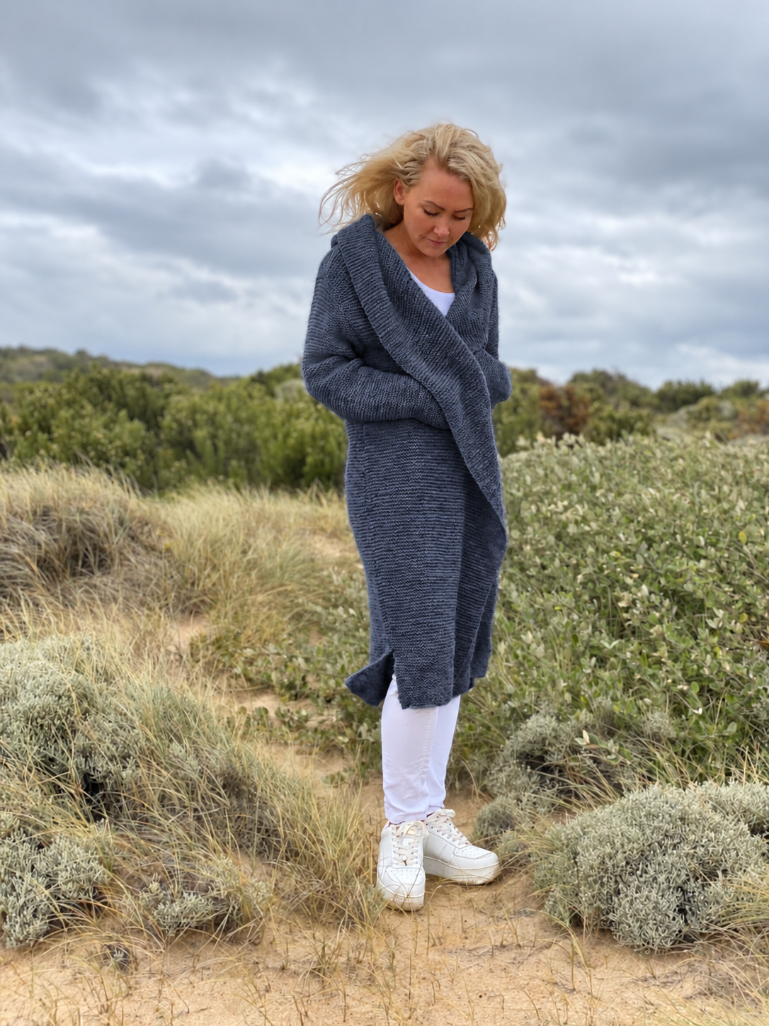 Elna hooded cardigan #133 in denim blue, knitted in chunky Scandi Soft XL and worn wrapped over white jeans