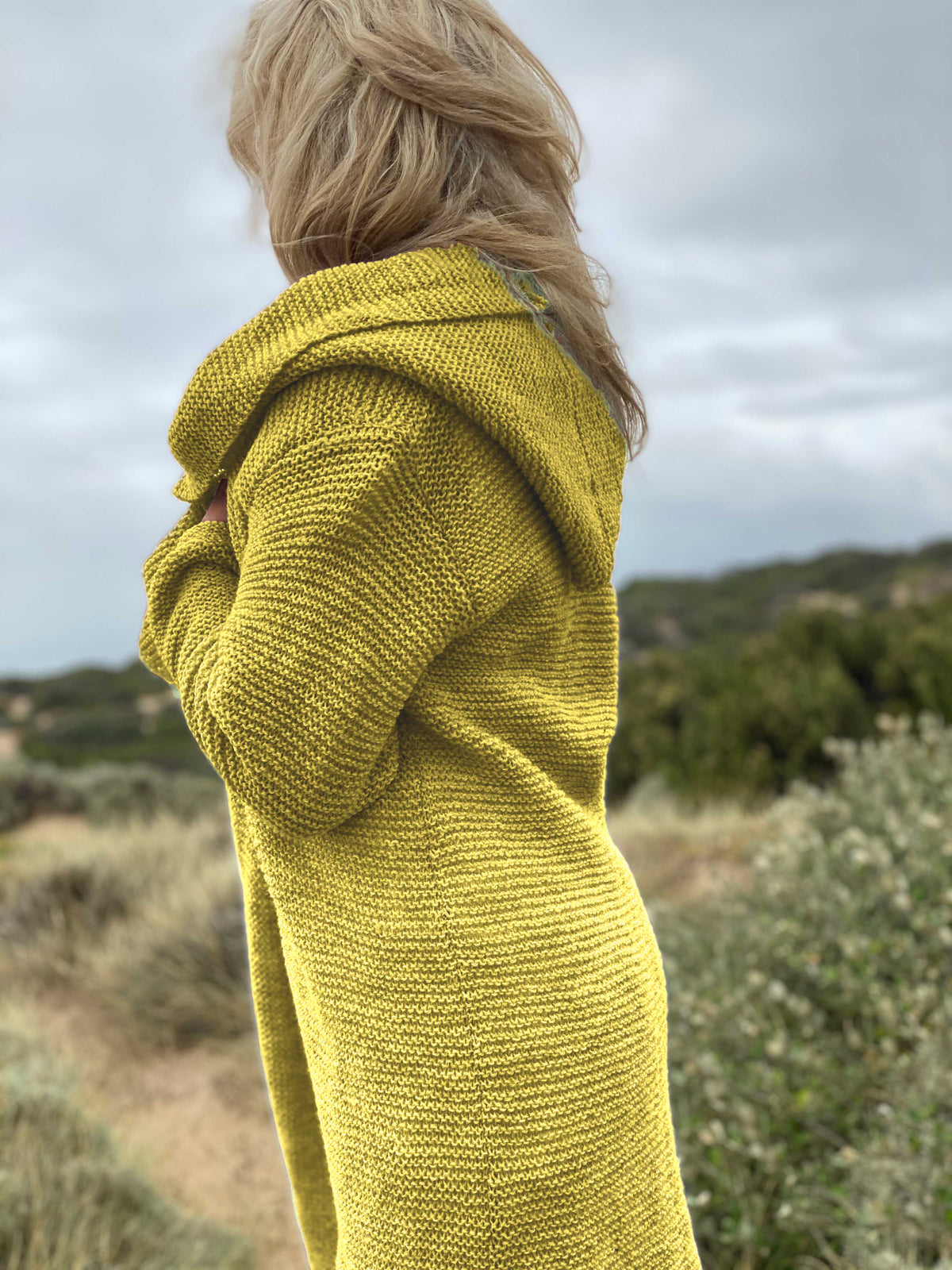 Side view of the Elna hooded cardigan #133 in chartreuse, showing the hood and the garter stitch texture of Scandi Soft XL