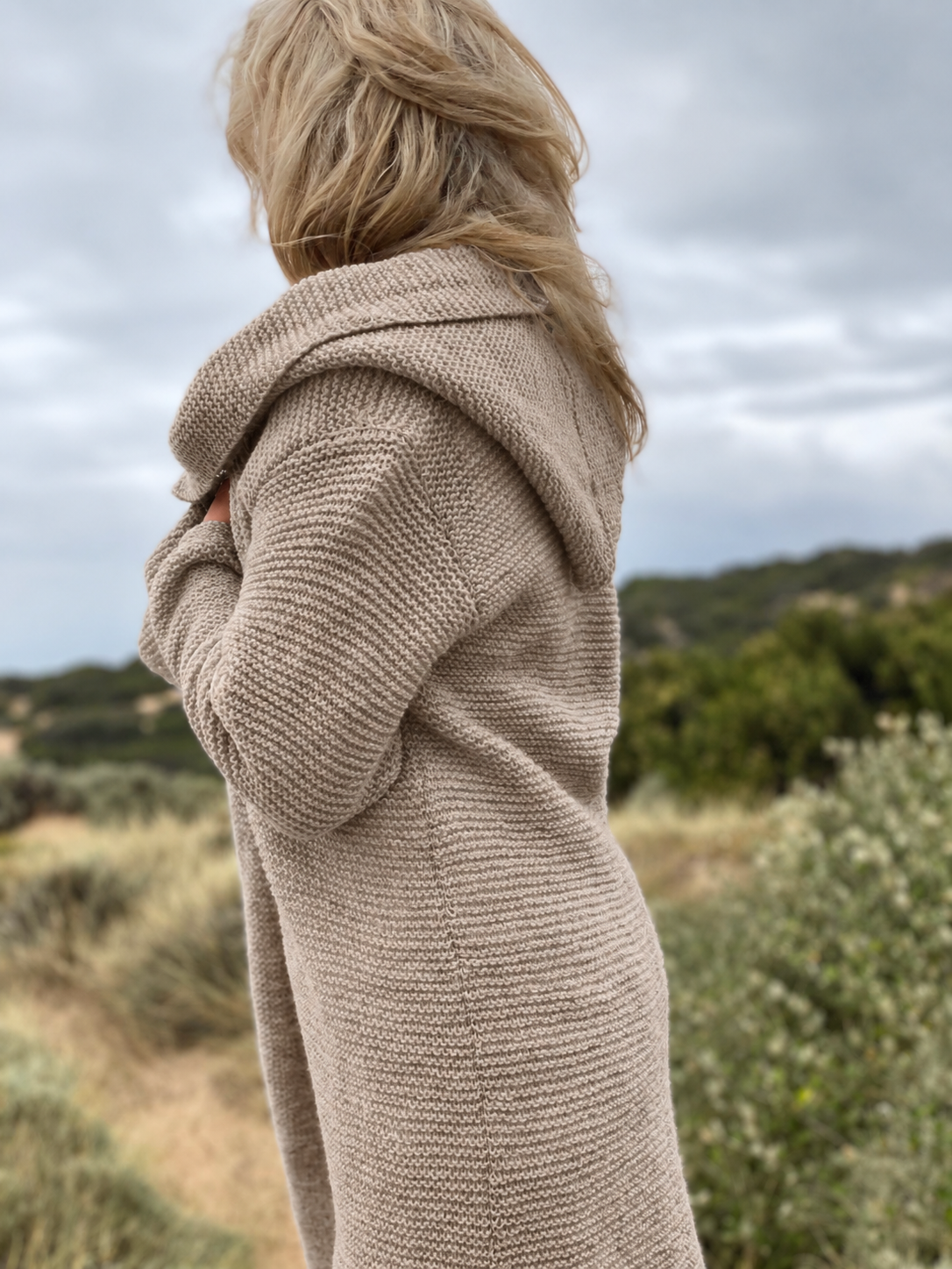 Elna hooded cardigan #133 in putty, seen from the side with the hood resting on the shoulders, knitted in chunky Scandi Soft XL
