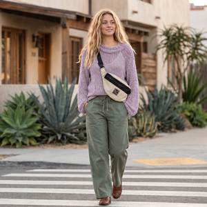Tora Loose Sweater #141 in lilac, worn with green trousers on a sunny street
