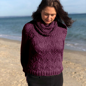 Woman on the beach wearing the Ingrid lace jumper #149 knitted in Snö Mulberry