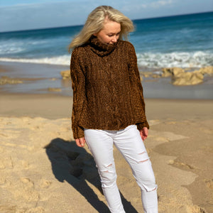 Woman on the beach wearing the Hedda Cable Roll Neck #150 knitted in Scandi Wool Toffee