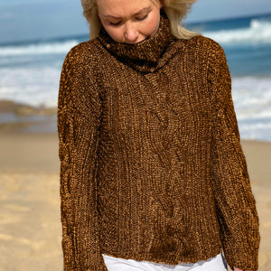 Woman walking on the beach in the Hedda Cable Roll Neck #150 knitted in Scandi Wool Toffee