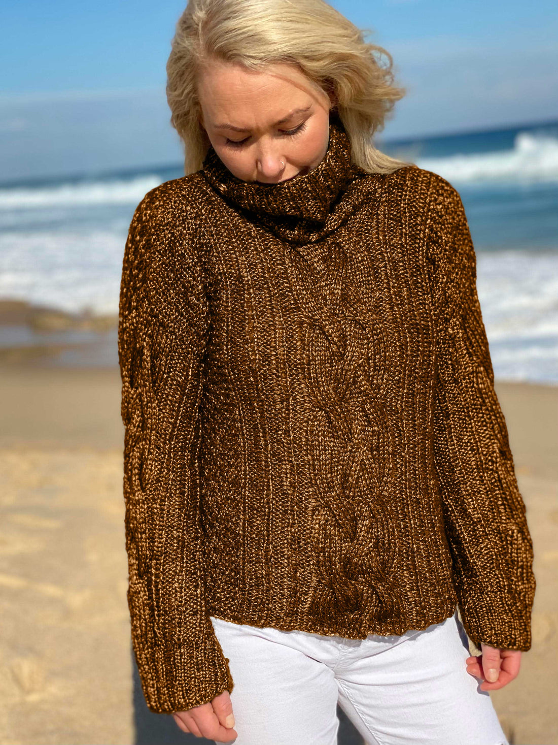 Woman walking on the beach in the Hedda Cable Roll Neck #150 knitted in Scandi Wool Toffee