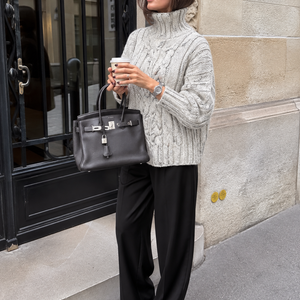 Hedda Cable Roll Neck #150 in ice, worn with black trousers on a city street