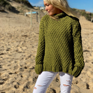 Woman on the beach wearing the Classic Roll Neck sweater #185 in olive