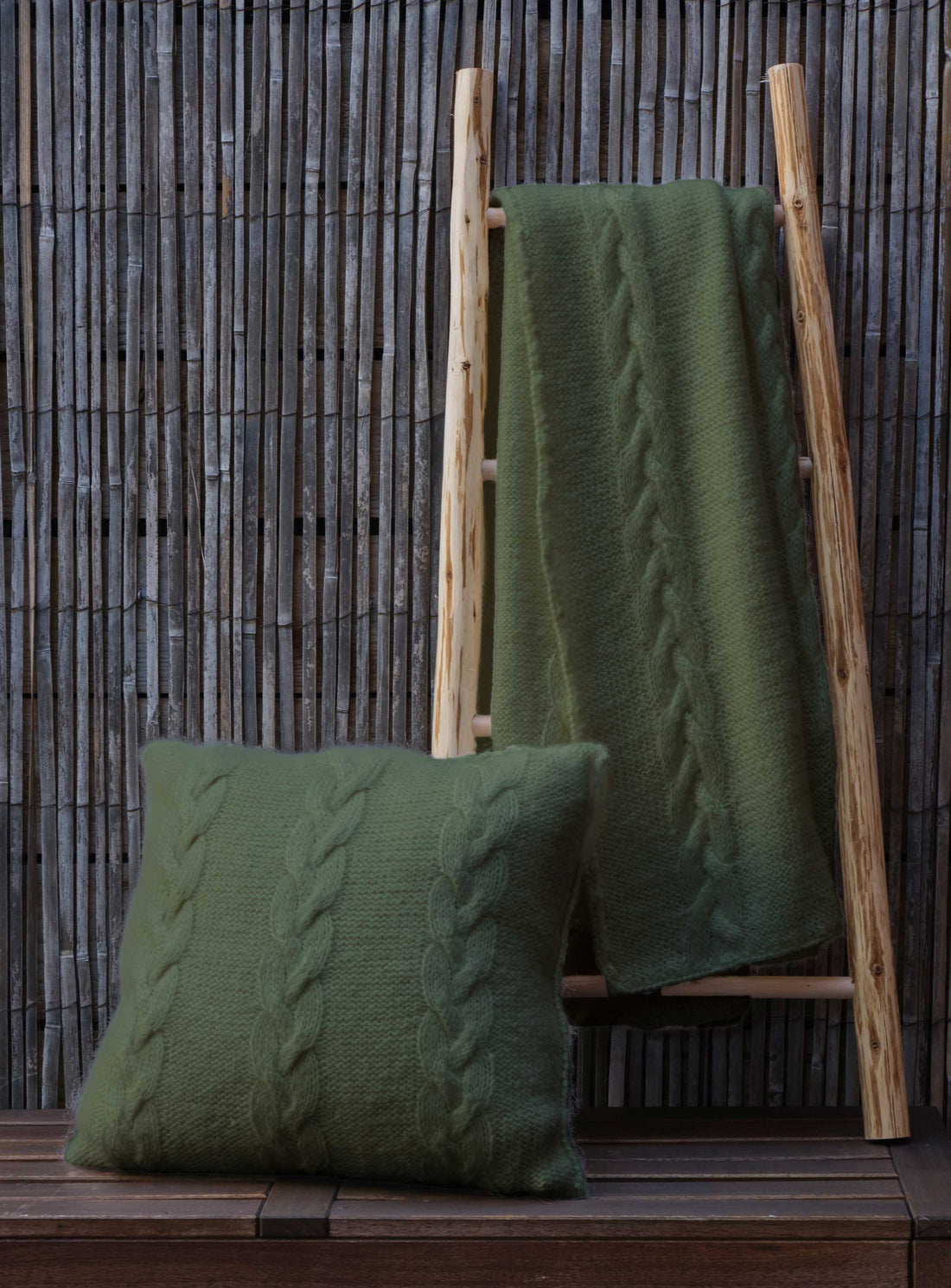 The Cable Cushion and Throw set #205 knitted in Scandi Wool Eucalyptus, shown on a wooden ladder