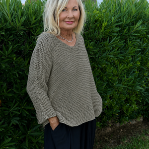 Vilja sweater #301 in eucalyptus, worn loose over dark trousers in a garden
