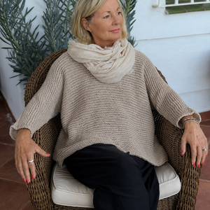 Vilja sweater #301 in linen, worn relaxed in a wicker chair