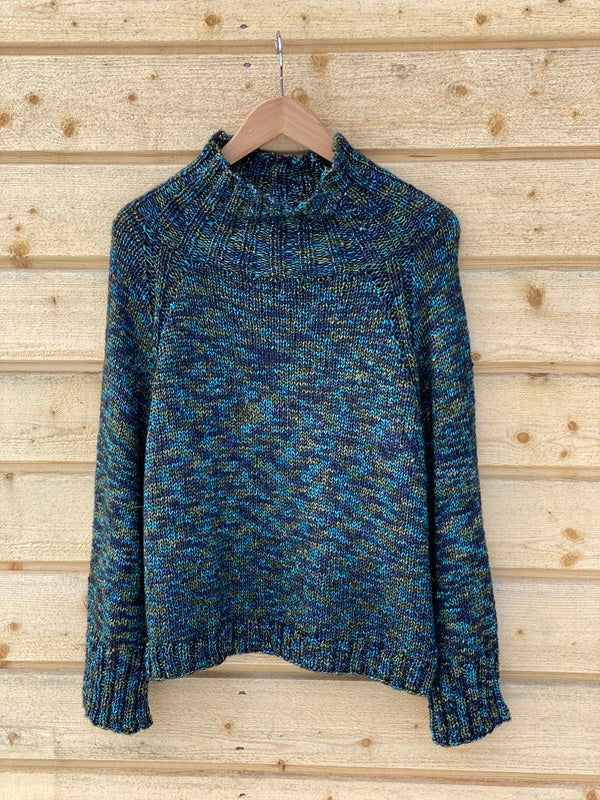 Nova Basic Sweater #304 in turquoise on a hanger, a seamless top-down raglan with a high collar