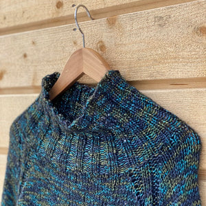 Close-up of the ribbed high collar and raglan shoulder of the Nova sweater #304 in turquoise
