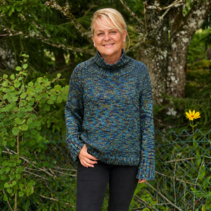Nova Basic Sweater #304 in turquoise, a shimmering Snö jumper worn in a garden