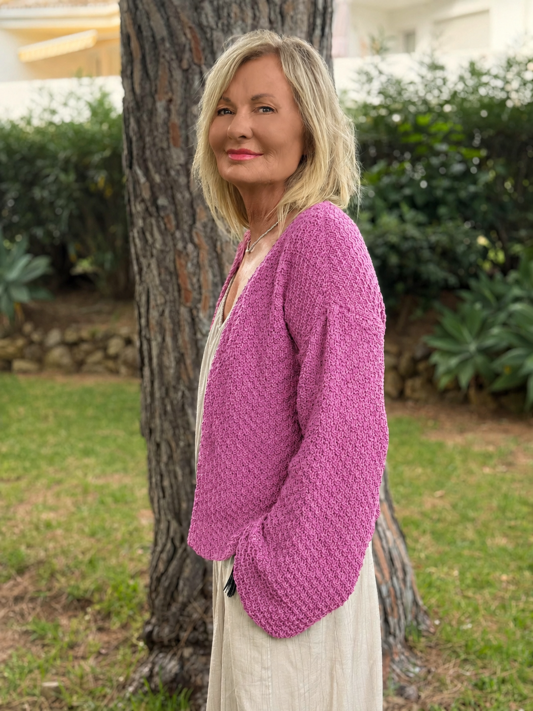 Woman wearing the Super Easy Cardigan #316 in wild rose, knitted in chunky Scandi Soft XL and worn open over a cream outfit