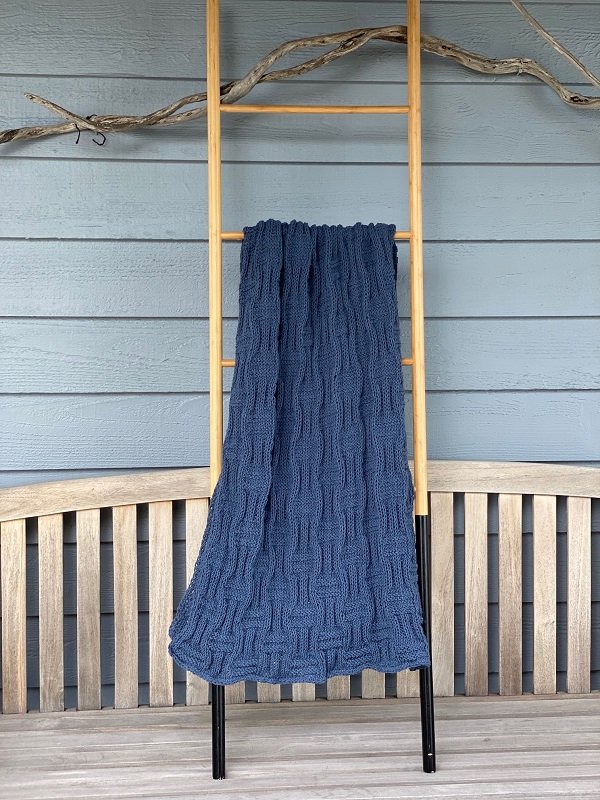 The Basket Throw #222 in indigo hanging on a wooden ladder