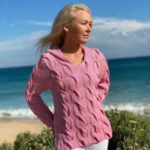 Woman on the beach wearing the Hooded Cable Jumper #172 in pink