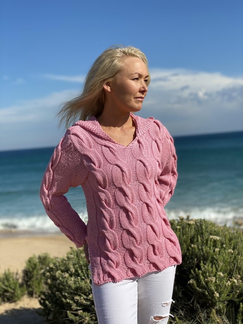 Woman on the beach wearing the Hooded Cable Jumper #172 in pink