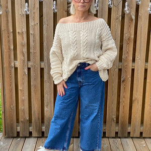 Woman wearing the Elisabeth cable jumper #113 in ecru with wide blue jeans